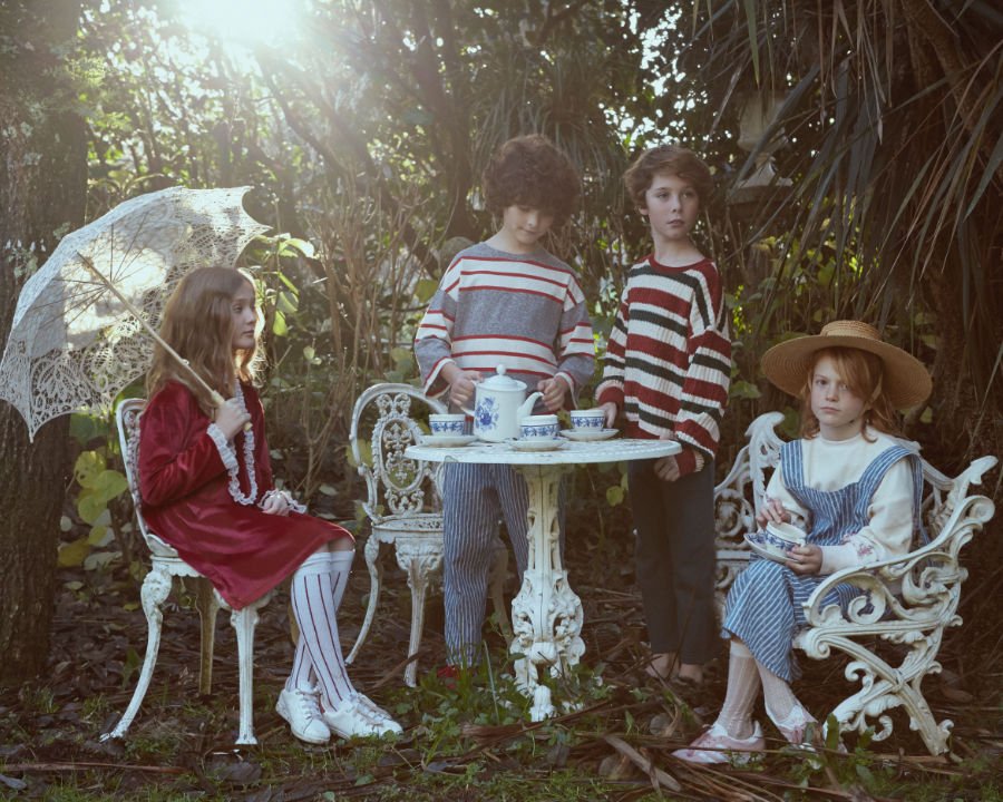 Eine entzückende Teegesellschaft: Unter dem Baum sitzt Alice in einem beerenroten Samtkleid von FISH & KIDS